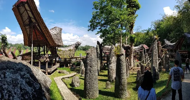 Standing stones on the ceremonial ground at Bori, tongkonan behind